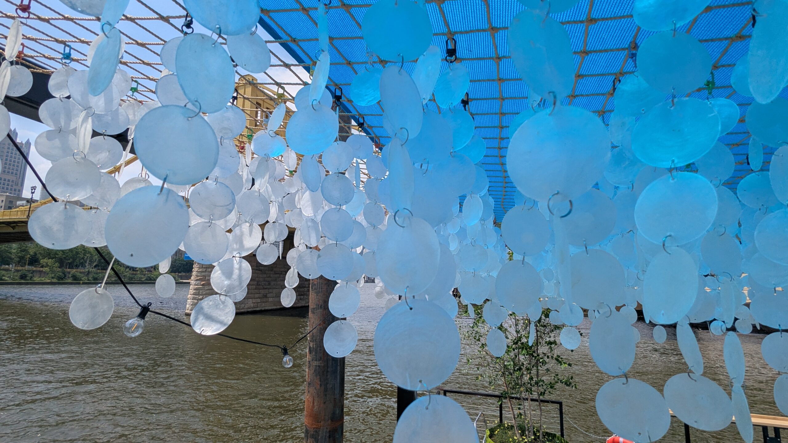 A series of round shells are strung together and hung from a ceiling structure.