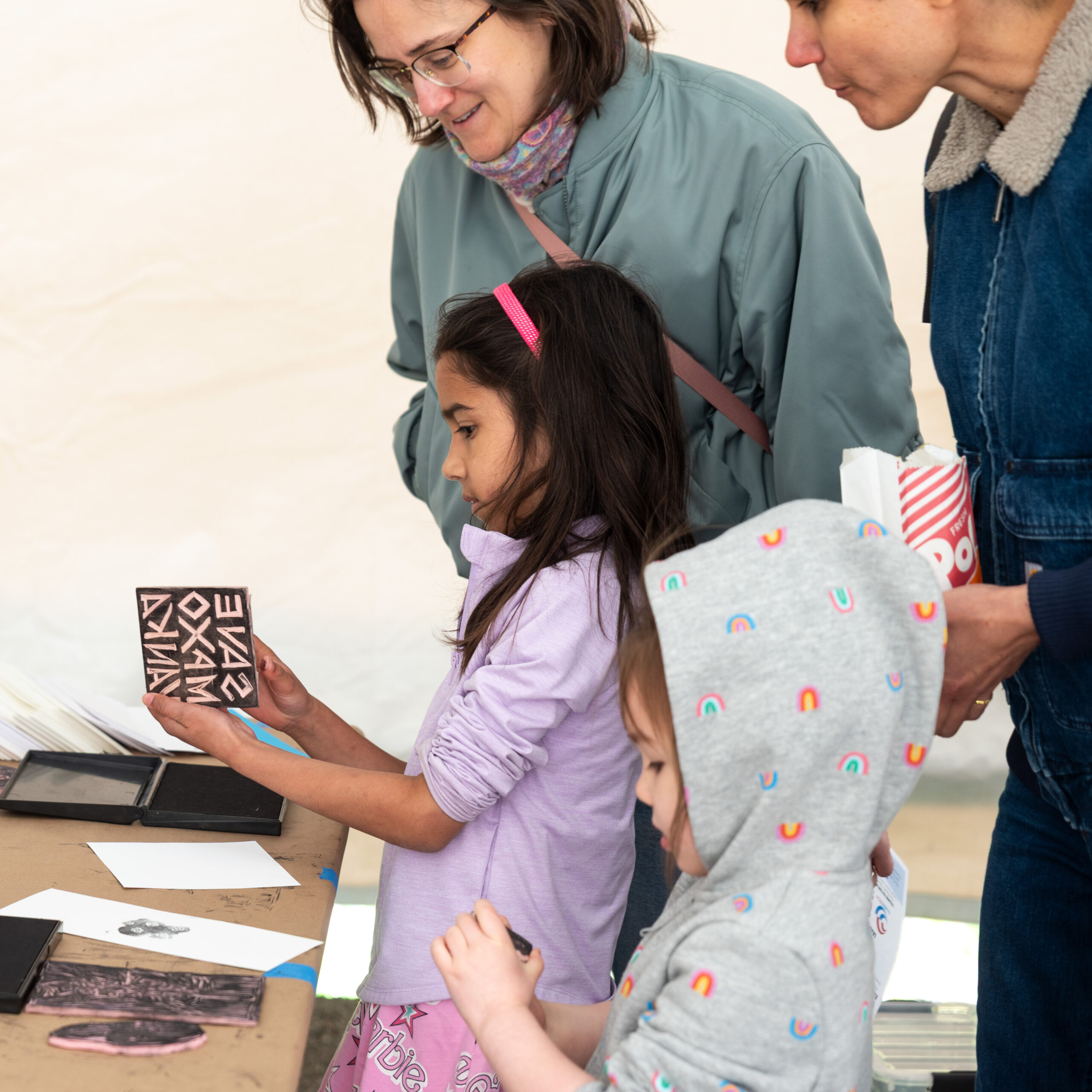 vanka-block-party-2026-block-printing Child holding "Save Maxo Vanka" rubber stamp at block party.